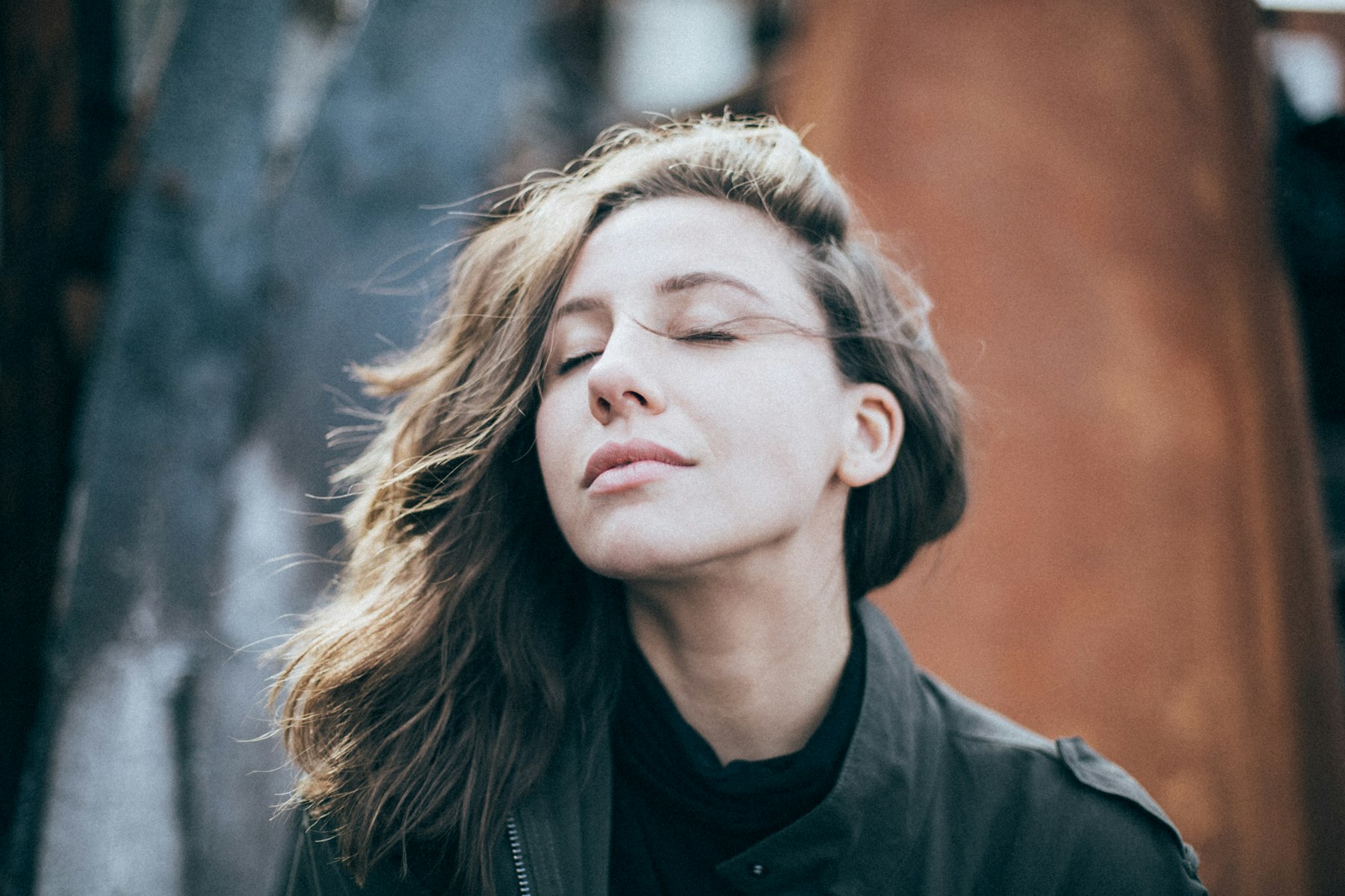 Mujer con los ojos cerrados, respirando al aire libre bajo luz natural.
