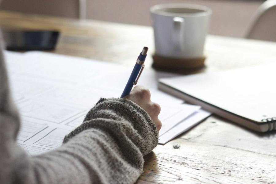 Manos escribiendo notas sobre una mesa de trabajo.